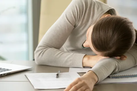 Eine erschöpfte Mitarbeiterin, die ein hohes Arbeitspensum bewältigen muss, leidet unter psychischen Belastungsfaktoren. © Shutterstock, fizkes