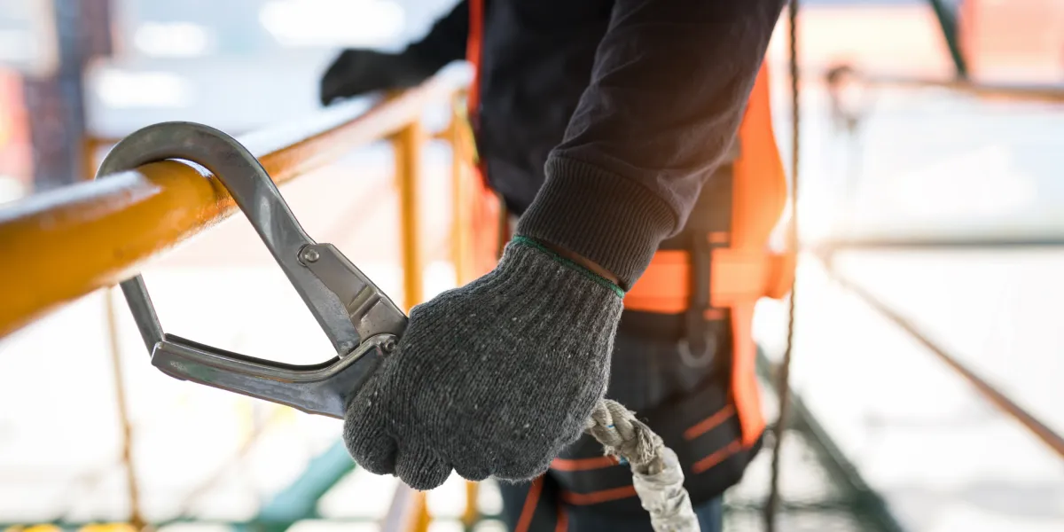 Der Mitarbeiter sichert sich bei der Arbeit mit einem Seil ab, um sich vor Arbeitsunfällen zu schützen. © Shutterstock, Aunging