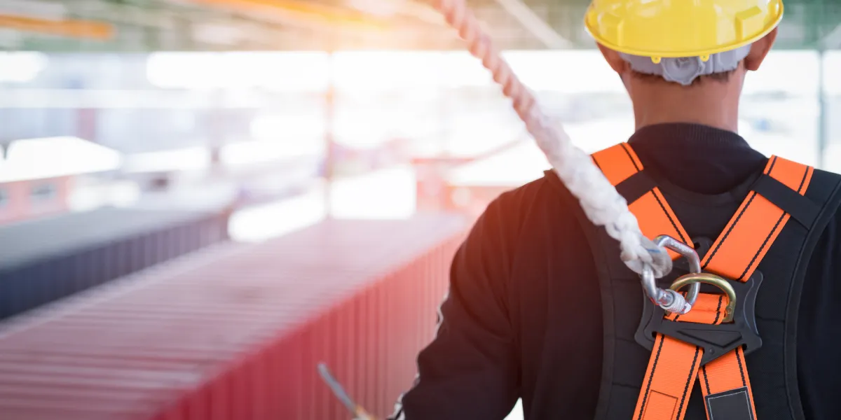 Mitarbeiter trägt Helm und ist mit Seil gesichert. Die Themen Sicherheit und Gesundheit am Arbeitsplatz sind für Arbeitgeber und -nehmer essentiell. © Shutterstock, Aunging