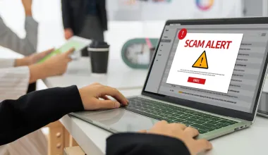 Ein Mitarbeiter wird durch eine Meldung auf seinem Laptop über einen Hackerangriff informiert.