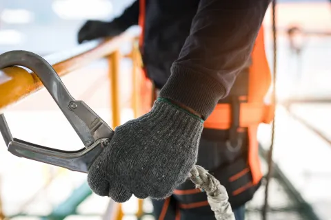 Der Mitarbeiter sichert sich bei der Arbeit mit einem Seil ab, um sich vor Arbeitsunfällen zu schützen. © Shutterstock, Aunging