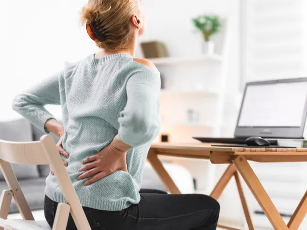 Mitarbeiterin leidet an Rückenschmerzen im Homeoffice. © Shutterstock, AstroStar
