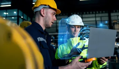 Zwei Mitarbeiter in Schutzkleidung unterhalten sich über die Maßnahmen, die die KI zum Arbeitsschutz vorgeschlagen hat. © Adobe Stock, Kannapat