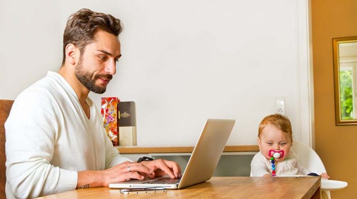 Ein Vater vereinbart Beruf und Familie, indem er im Homeoffice arbeitet. Daneben sitzt sein Kleinkind. © Adobe Stock, Jürgen Fälchle