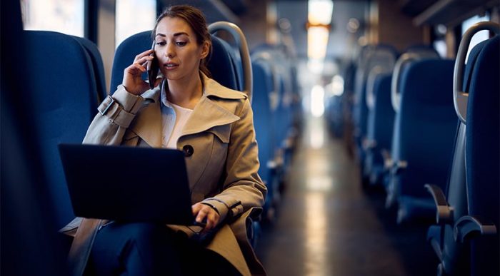 Eine Mitarbeiterin fährt mit dem Zug und telefoniert, während sie an ihrem Laptop ist. Das Wachstumschancengesetz erhöhte die Verpflegungspauschalen bei Dienstreisen. © Adobe Stock, Drazen