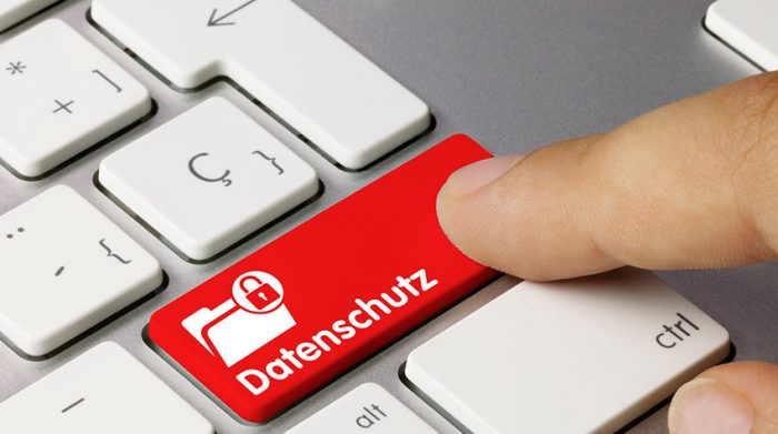 Finger drückt rote Taste mit Aufschrift „Datenschutz“ auf einer Computertastatur.