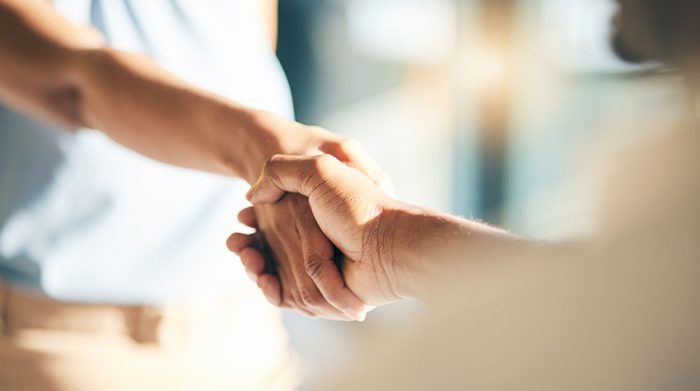 Zwei Personen reichen sich die Hand, symbolisch für Vertrauen, Zusammenarbeit und gegenseitige Unterstützung im BEM-Prozess.