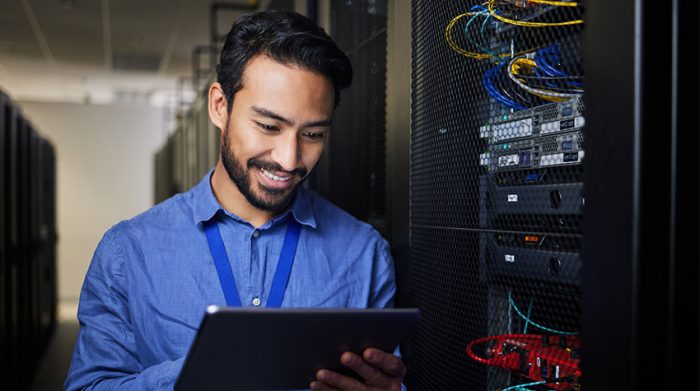 Mitarbeiter steht mit Tablet in einem Serverraum. Mit den ISO 27001 Standards kann sein Unternehmen Sicherheitsvorfälle minimieren. © Adobe Stock, Nina L/peopleimages.com