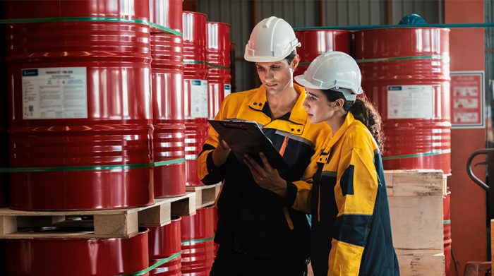 Mitarbeiter arbeiten in einem Lager voller Gefahrstoffbehälter. Für sie ist eine Pflichtvorsorge vorgesehen. © Adobe Stock, InfiniteFlow