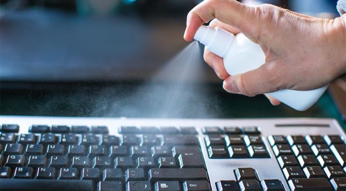 Ein Mitarbeiter desinfiziert die Computertastatur, die ein anderer vor ihm nutzte. Auf diese Weise werden Keime im Büro vermieden. © Adobe Stock, aerogondo