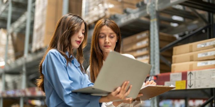 Mitarbeiterinnen stehen im Lagerraum mit Klemmbrett und Laptop und prüfen entsprechend der Kaizen-Methodik auf Verbesserungspotenzial. © Adobe Stock, Art_Photo