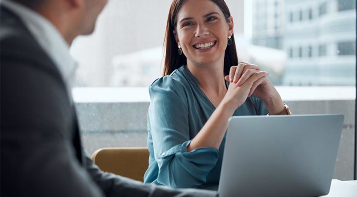 Eine Mitarbeiterin freut sich über das positive Feedback, das sie von ihrem Vorgesetzten erhält.© Adobe Stock, Micah C/peopleimages.com